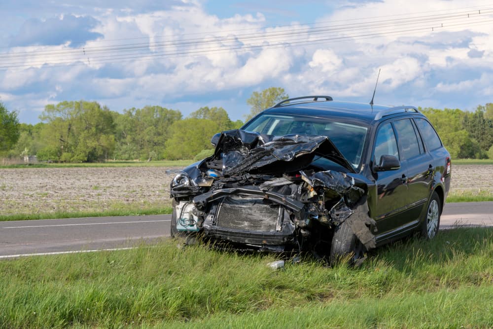 After an accident, a car is on the side of the road, probably a total loss.